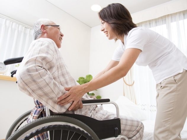 車椅子に乗った男性を介護する介護士の画像