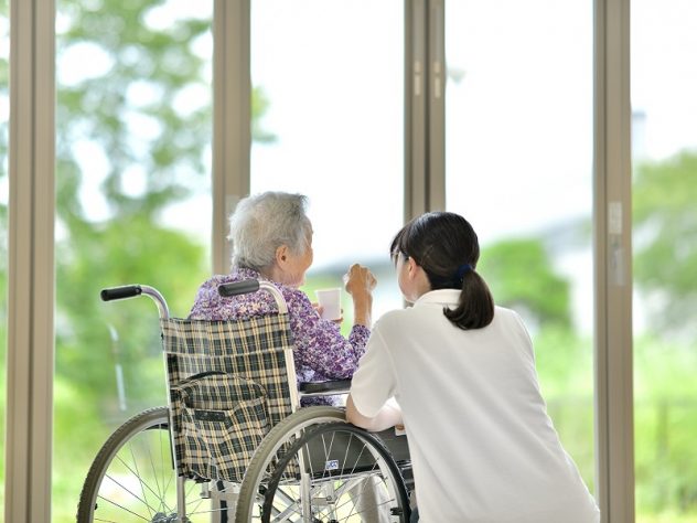 老人介護施設の窓辺でくつろぐ高齢者の画像