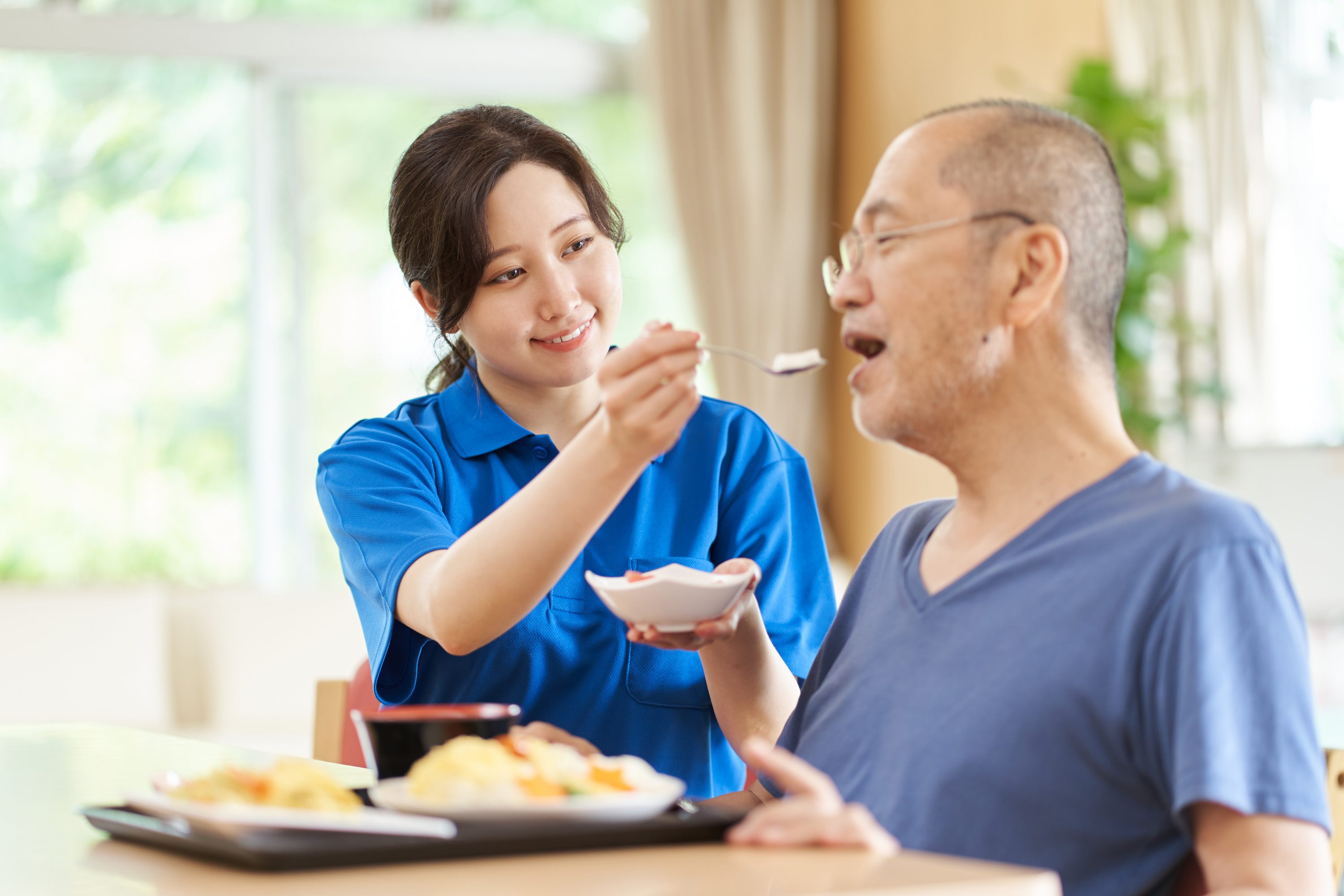 高齢者に食事の介助をする介護士のイメージ