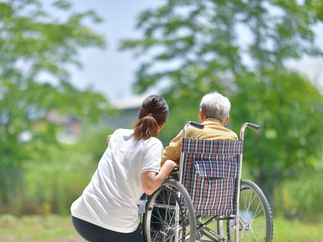 車椅子の高齢者に寄り添う女性介護スタッフ