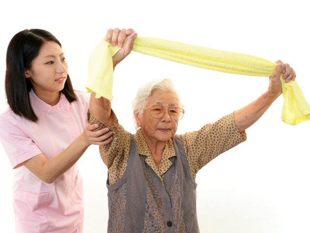 体操をしている老人と補助をしている介護スタッフの画像