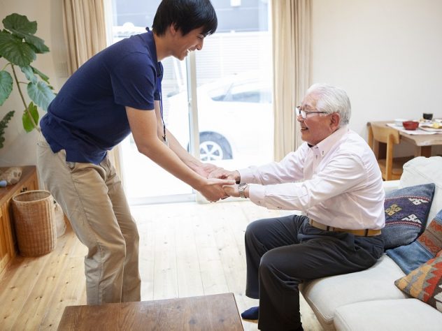 立ち上がりの介助をする男性介護士の画像
