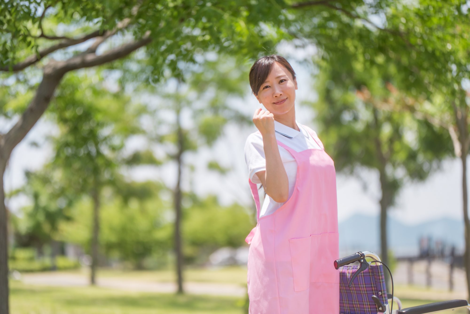 車椅子を押しガッツポーズで振り向く女性介護士の画像