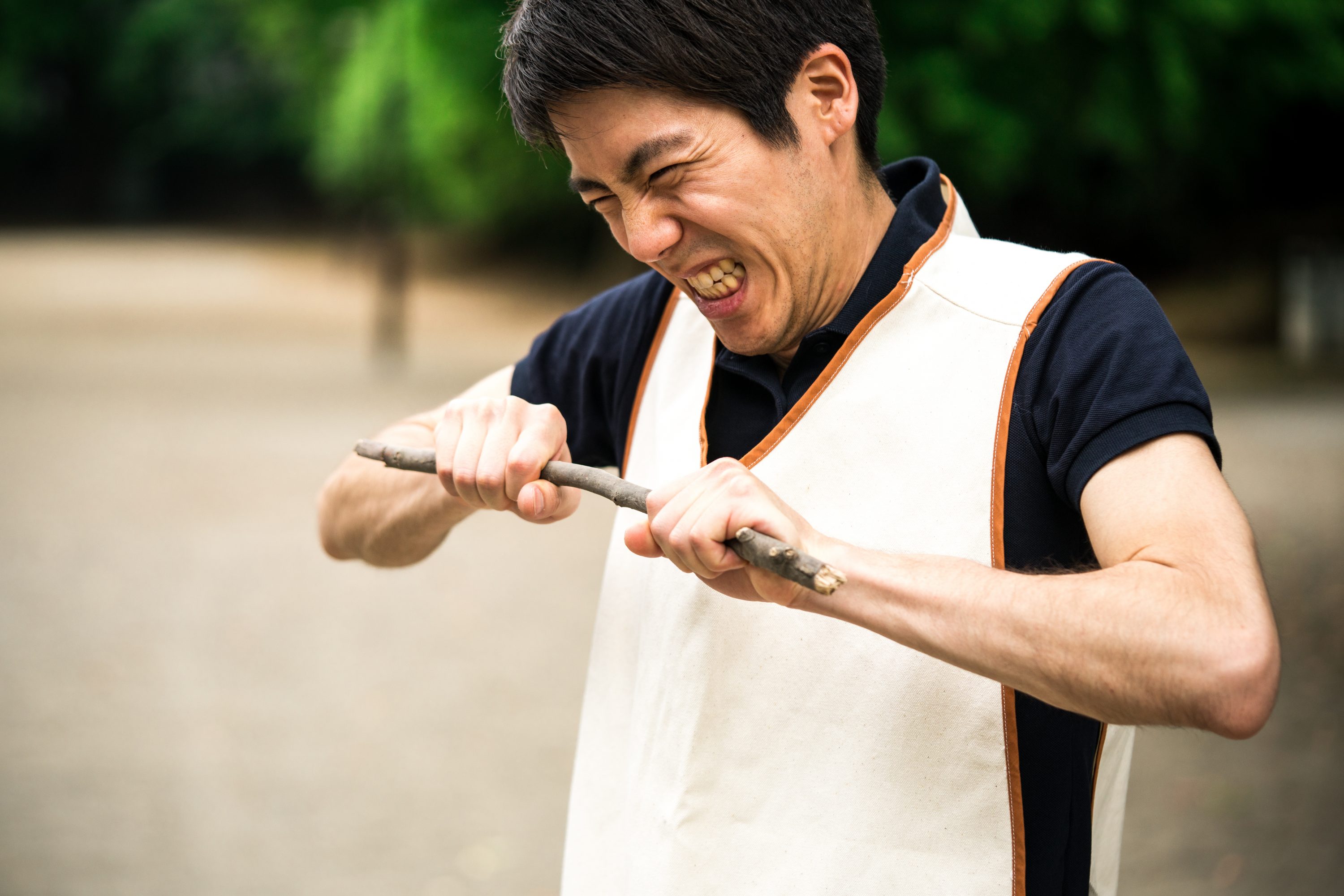 棒を握りしめて怒りを抑える介護士の画像