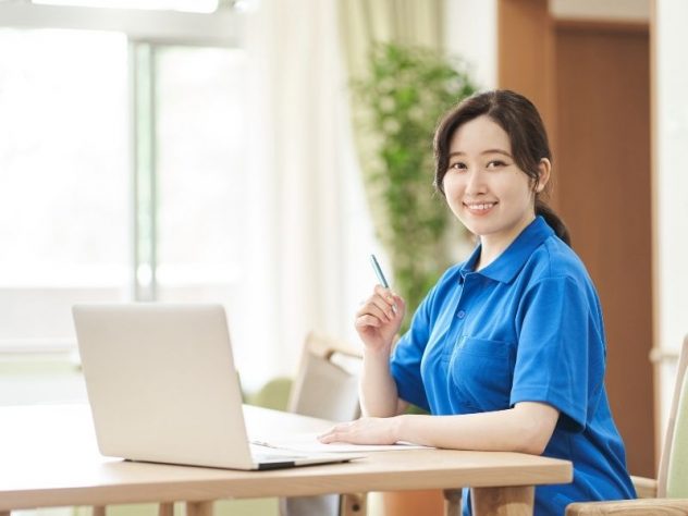 パソコンを開き勉強をする女性介護スタッフの画像