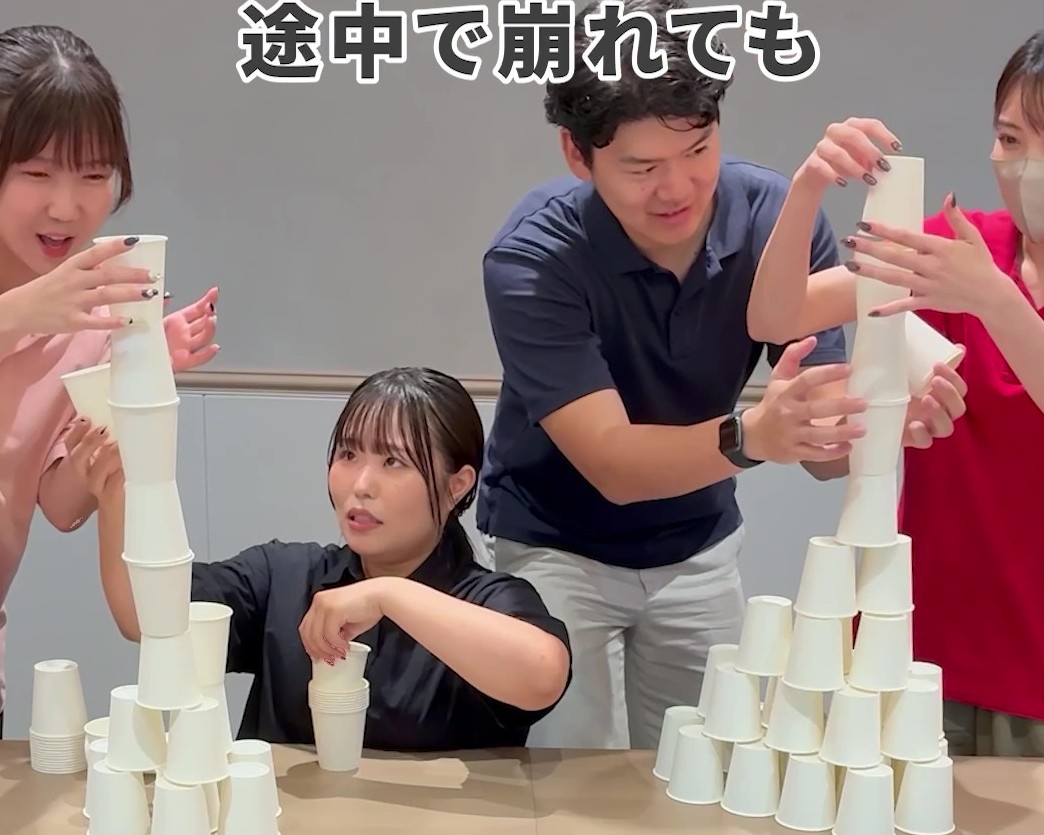 2チームに分かれて紙コップを高く積み上げている様子