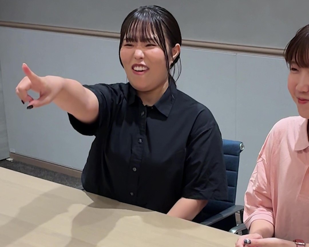 女性が笑顔で指差しをしている画像