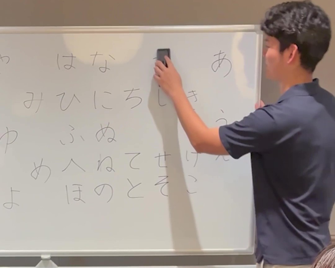 男性がホワイトボードに書かれた文字を消している様子